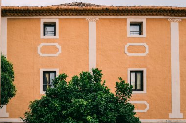 Simetrik Pencereli ve Yeşillik Bahçeli Terracotta Binası. Bulutlu bir günde doğal dokunuşları olan klasik Avrupa mimarisi