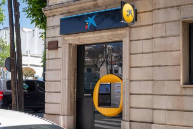 Barselona, İspanya-4 Haziran 2024. Müşteriler güneşli bir şehirde CaixaBank ATM 'sinde para transferi yapıyor..
