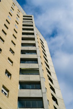 Mavi gökyüzüne karşı modern bir apartmanın alçak açılı görüntüsü..