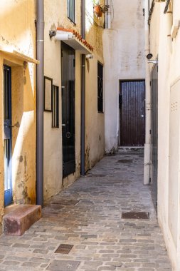 Beyaz duvarlar ve renkli kapılarla kaplı dar bir ara sokağa çıkan bir kaldırım taşı yolu. Badalona, İspanya