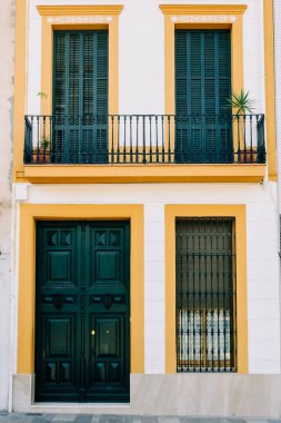 Koyu yeşil kapılı ve sarı balkonlu tarihi bina cephesi. Kentsel mimaride tarih ve tasarım arasındaki uyum