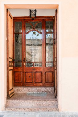 Modern stil bir bina içinde süslü ahşap bir kapı seti. Karmaşık cam işçiliği ve klasik tasarım sergileniyor..