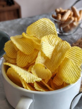 Arka planda atıştırmalıklar olan bir tabak patates cipsi..