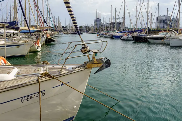 Badalona, İspanya - 30 Aralık 2024. İspanya 'nın Badalona limanında demirlemiş yelkenlilerin modern binaları ve bulutlu bir gökyüzünün altında sakin suları olan yakın görüntüsü..