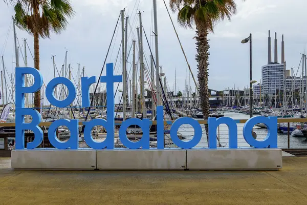 Badalona, İspanya - 30 Aralık 2024. Porto Riko Badalona marinasının manzarasında yelkenliler, modern binalar ve ön planda belirgin mavi bir 