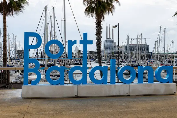 Badalona, İspanya - 30 Aralık 2024. Porto Riko Badalona marinasının manzarasında yelkenliler, modern binalar ve ön planda belirgin mavi bir 