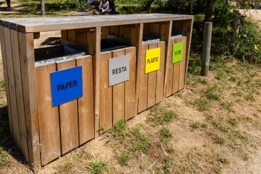 Renys de Mar, İspanya - Haziran 03, 2025. Kağıt, plastik, cam ve genel atık için ahşap geri dönüşüm kutuları doğal bir ortamda sorumlu bertaraf edilmesini teşvik eder
