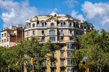 Süslü mimarisi ve ağaç kaplı caddesi olan klasik Avrupa apartmanı, İspanya 'nın orta Barselona şehrinde mavi gökyüzünün altında yer alıyor..