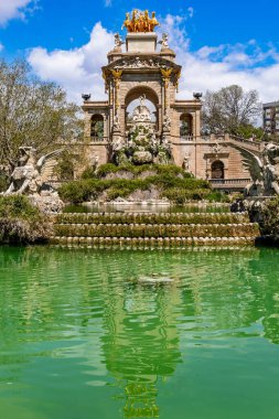 Barselona, İspanya-21 Nisan 2025. Ciutadella Park, Barselona, İspanya 'daki altın kuadriga heykeliyle anıtsal Cascada çeşmesi bulutlu güzel bir gökyüzünün altında parlıyor.