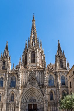Açık mavi gökyüzüne karşı Barselona Katedrali 'nin ana giriş ve kulelerinin detaylı görüntüsü.