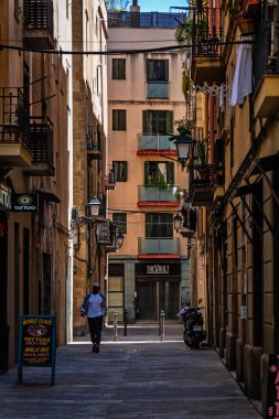 Barselona, İspanya-21 Nisan 2025. Barselona, İspanya 'nın Barri Gtic bölgesindeki tarihi Gotik Mahallesi' nde dar ve atmosferik bir sokakta yürüyen bir insan...
