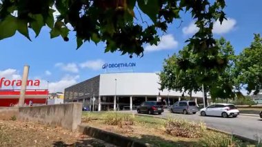 Barselona, İspanya-3 Ağustos 2025. Mavi gökyüzüne karşı geniş bir dekatlon mağazasının dış görünüşü, ön planda hareketli bulanık arabalar.