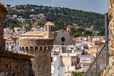 Yüksek açılı bir bakış açısı, İspanya 'nın Barok Kilisesi' nin Sant Vicent kentindeki Tossa de Mar kentinin ön planında Vila Vella 'nın ortaçağ taş savunma kulesini çerçeveler.