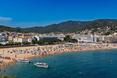 Girona, İspanya-12 Ağustos 2025. Tossa de Mar, Costa Brava, İspanya, Vila Vella kalesi ve Akdeniz 'e bakan taş kuleleri üzerinde. Antik duvarların altında, at nalı Platja Gran