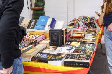 Barselona, İspanya-23 Nisan 2023. 23 Nisan 'da, Aziz Jordi gününde, insanlar kitapların ve kırmızı güllerin hediye edildiği Katalonya' da düzenlenen geleneksel bir festival olan sokakta kitaplara bakıyorlar..