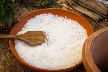 Ahşap bir kaşık, deniz tuzu da dahil olmak üzere taze malzeme yığınının tepesinde oturur. Mutfak yapımı her yemek için mükemmel bir ilave sağlar.