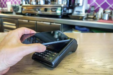 Ödeme terminalinde ödeme yapmak için akıllı telefon kullanan bir restoran müşterisi. Tpv.