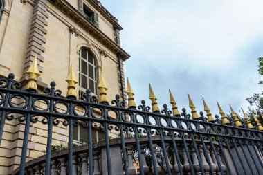 Etrafı çitlerle çevrili eski bir bina parlak bir gökyüzüne karşı duruyor ve gezginlerin zengin tarihini keşfetmeleri için ikonik bir hedef haline getiriyor..