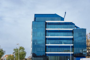 İş bölgesi binaları ağaçlarla ve mavi gökyüzüyle şehir caddesine dizilmiş durumda...