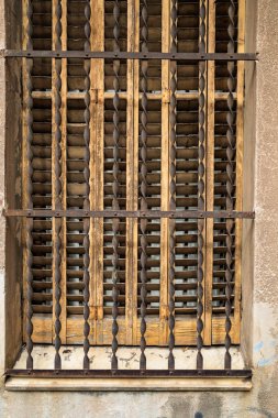 Old wooden window with metal bars and shutters.