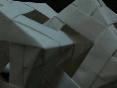 Katlanmış kağıdın geometrik kıvrımlarını ve kıvrımlarını vurgulayan, karmaşık beyaz kağıt origami şekillerini gösteren yakın plan bir resim.