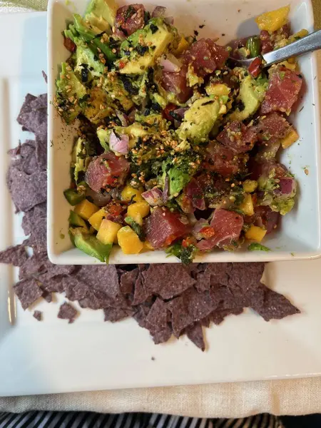 Canlı bir kâse ev yapımı avokado, doğranmış domates, soğan, kişniş ve baharatla yapılmış, yanında gevrek mavi mısır tortilla cipsi.. 