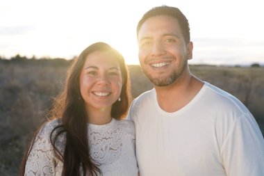 Neşeli ve mutlu bir çift açık havada güneşli bir günün tadını çıkarıyor. Sıcak, sevgi ve neşe saçıyor.