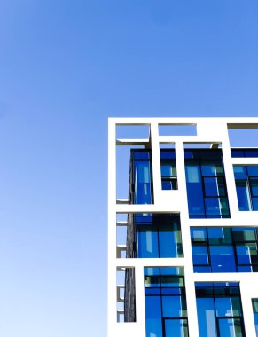 Mavi gökyüzüne karşı modern bir binanın yakın görüntüsü.