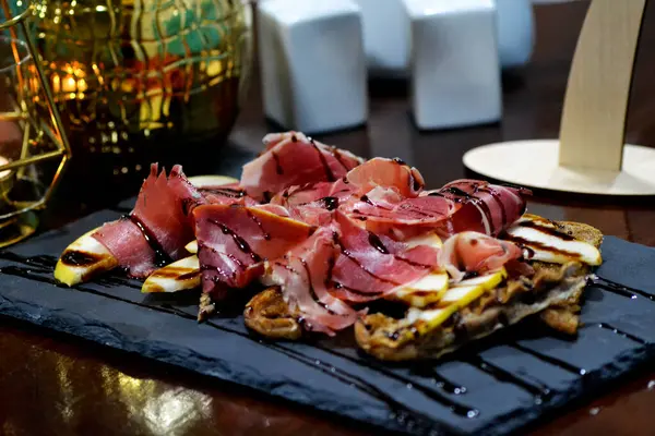 Farklı peynir, jambon ve ahşap arka planda jambon içeren aperatifler.