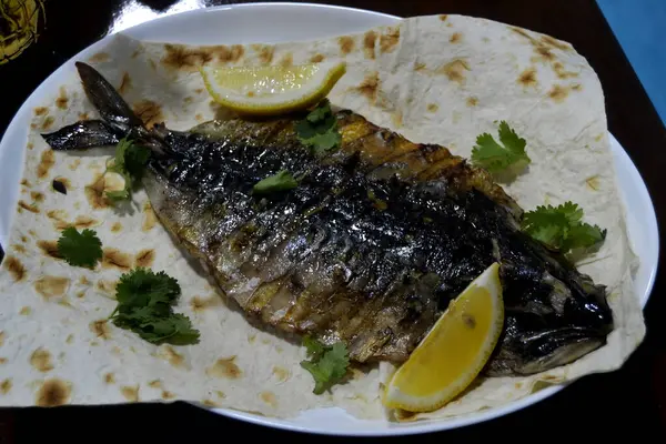 Maydanozlu kızarmış balık ve limon dilimleri.