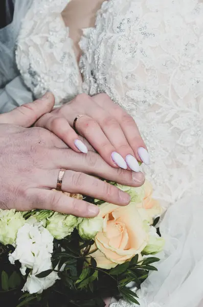 Gelin ve damadın ellerinde bir buket çiçek ve alyans. yüksek kaliteli fotoğraf
