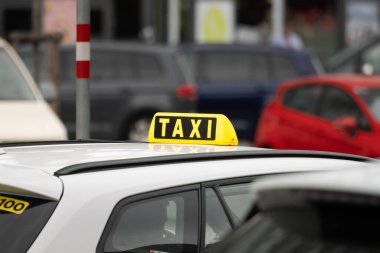 Avusturya 'da yakın plan bir araba için taksi tabelası. Kalabalık bir şehirde şoför bekliyor. Sarı sembol çatıya monte edilmiş. Kentin iç kesimlerinde turistler için ulaşım hizmeti.