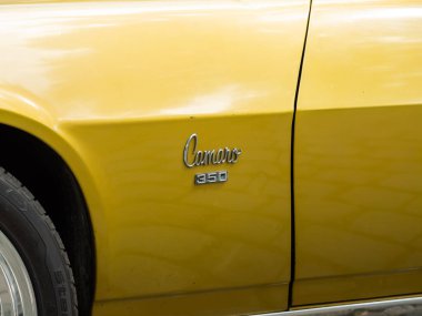 VIENNA, AUSTRIA - 28. Temmuz 2024: Chevrolet Camaro 350 logo tabelası. ABD 'li eski zamanlayıcı Placer Gold rengine boyanmış. Arabanın adının ayrıntıları..