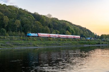 Saxon SWitzerland, Almanya - 22. Nisan 2025: Saxon İsviçre manzarasında Elbe nehrinin yanındaki VVVO treni. Toplu taşıma hattı S1 veya S2 de S-Bahn olarak adlandırılır ve kırmızı renklidir.