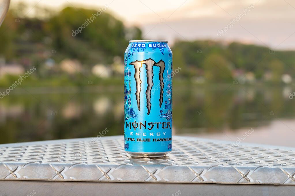 DRESDEN, GERMANY - 22. April 2025: Monster Energy Ultra Blue Hawaiian beverage. The zero sugar energy drink can is standing on an aluminum tread plate. Sport boat on a river background.