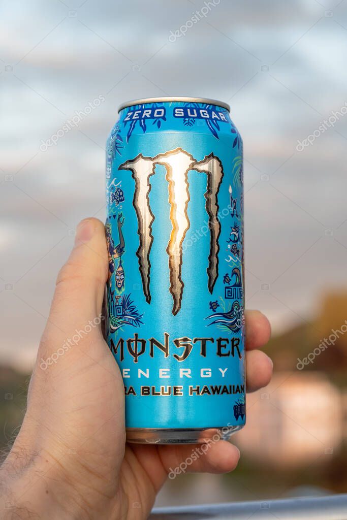 DRESDEN, GERMANY - 22. April 2025: Monster Energy Ultra Blue Hawaiian beverage. Holding the zero sugar energy drink in the hand. Sunset sunlight illuminating the can while being outdoors.