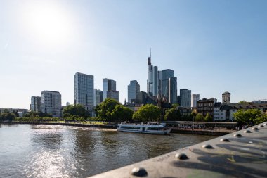 FRANKFURT, Almanya - 13. Mayıs 2025: Finans bölgesinin Skyline 'ı ve Iron Footbridge' in ana nehri. Şehir merkezindeki gökdelen turistik eğlence ve iş yeri olarak kullanılıyor..