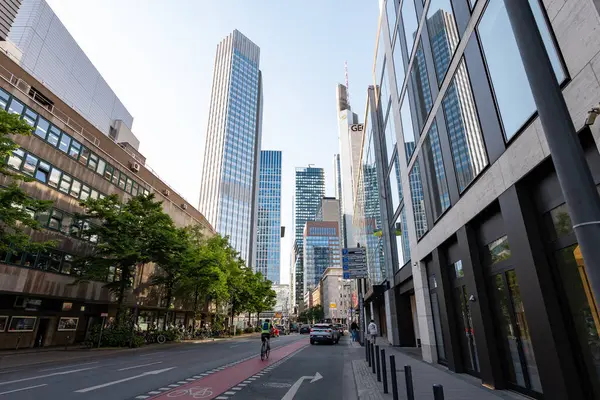 FRANKFURT, Almanya - 13. Mayıs 2025: Finans bölgesinde gökdelenli sokak manzarası. Gün batımında şehir merkezi hayatı. Kentsel alandaki işverenlerin ofis binaları.