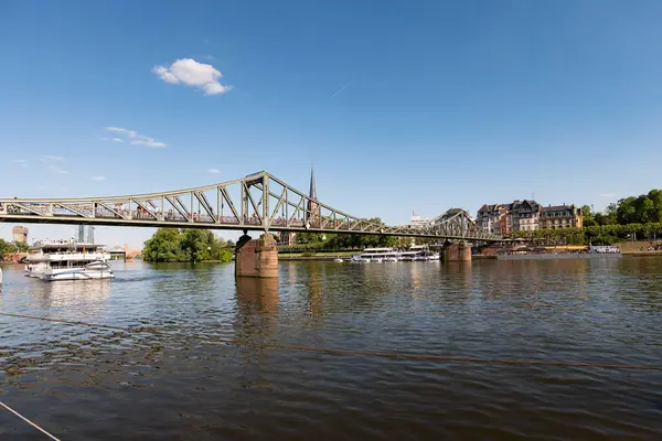 FRANKFURT, Almanya - 13. Mayıs 2025: Eiserner Steg (Demir Ayak Köprüsü) ana nehrin karşısındaki bina. FFM 'nin tarihi simgesi, bir seyahat merkezi ve kentteki kalabalık turistik merkezdir..
