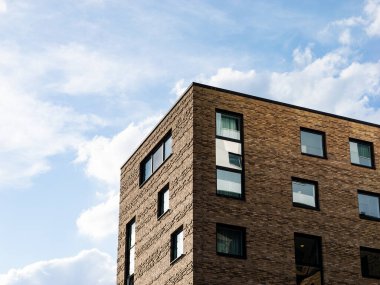 Çağdaş bina cephesi, koyu renkli tuğlalarla yakın plan. Dış tasarım 3 boyutlu desenli. Kare şeklindeki pencereler eve entegre edilmiştir.