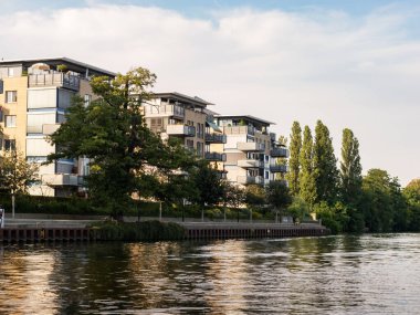 BERLİN, ALMANY - 11. Temmuz 2023: Treptow-Koepenick bölgesindeki Spree nehrinin yanındaki konut binaları. Rıhtımdaki apartman daireleri. Kiralık veya yatırım amaçlı gayrimenkul.