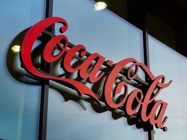 BERLİN, Almanya - 13. Temmuz 2023: Coca Cola markası ve içecek endüstrisinin logosu. Kırmızı harfler modern ofis binasının cam duvarının önünde. Dış taraftaki sembol.