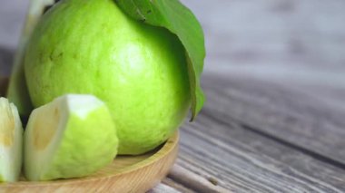 Çerçevenin sol yarısını kaplayan dönen guava tabakasının yan görüntüsü, tüm guava ve düzgün düzenlenmiş dilimlerle.