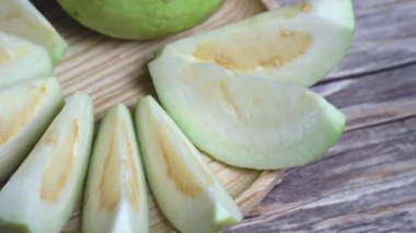 Tam guava ve düzgün sıralanmış dilimlerle dönen bir levhanın yakın açılı görüntüsü