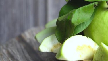 Yanında guava yaprakları olan bir tabağa yerleştirilmiş taze guava parçaları yakın plan.