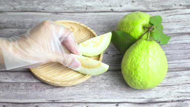 Dilimlenmiş guava parçaları gibi boş bir tabağın yanında iki guava.