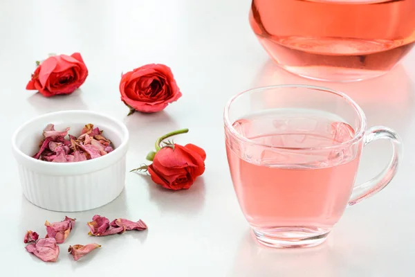Rose tea in a glass cup with dried roses in the background