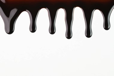 Beyaz arka planda çikolata şurubu damlıyor.