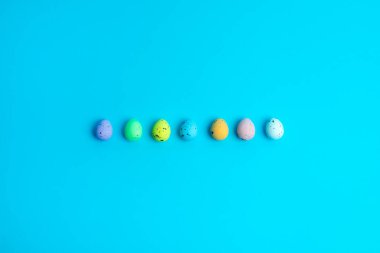 Minimalist Paskalya yumurtaları arka arkaya parlak turkuaz arka planda sergileniyor. Mevsimsel pazarlama, tasarım ve dijital içerik için ideal basit ama canlı bir tatil temalı kompozisyon.