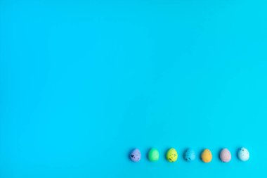 Minimalist Paskalya yumurtaları düzgün bir şekilde canlı bir turkuaz arka plana yerleştirilip tasarım esnekliği için negatif alan bırakırlar. Markalaşma veya reklam için modern ve yaratıcı bir mevsimsel kompozisyon.